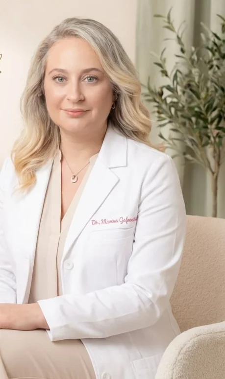 Dr. Marina Gafanovich, MD, in a white coat, seated